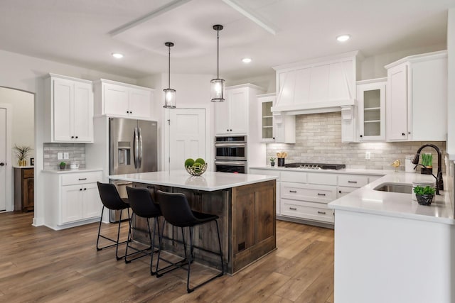 kitchen featuring a center island, appliances with stainless steel finishes, white cabinetry, decorative backsplash, and sink