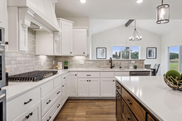 kitchen featuring sink, white cabinets, appliances with stainless steel finishes, and vaulted ceiling with beams