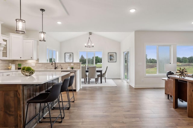 kitchen featuring a kitchen bar, decorative light fixtures, white cabinetry, sink, and a notable chandelier