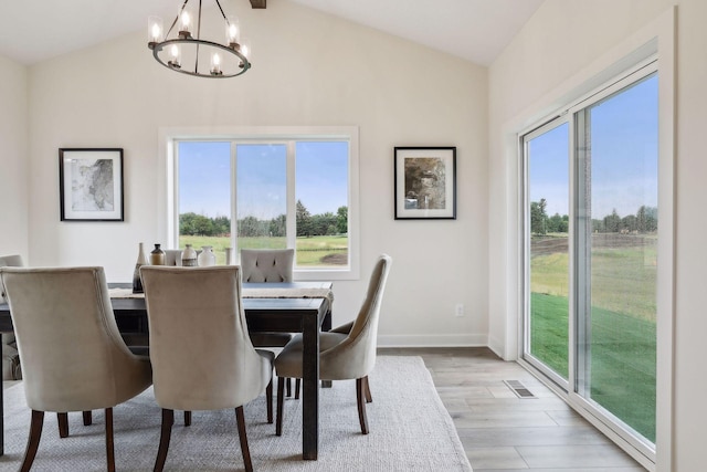 dining space with a chandelier, light hardwood / wood-style floors, and lofted ceiling