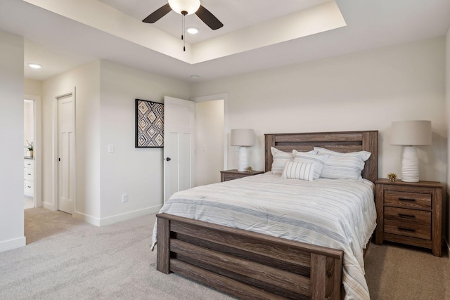 carpeted bedroom featuring a closet, a tray ceiling, and ceiling fan