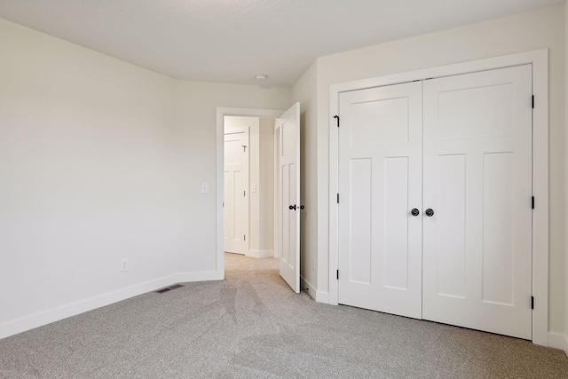 unfurnished bedroom with a closet and light carpet