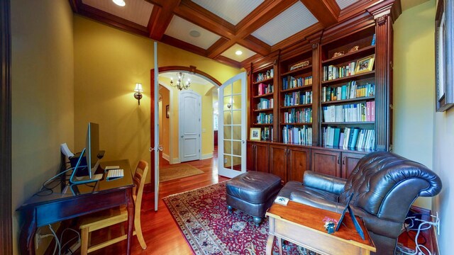 sitting room featuring coffered ceiling, beamed ceiling, a notable chandelier, hardwood / wood-style floors, and french doors