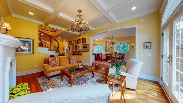 living room with ornamental molding, a healthy amount of sunlight, a notable chandelier, and hardwood / wood-style floors