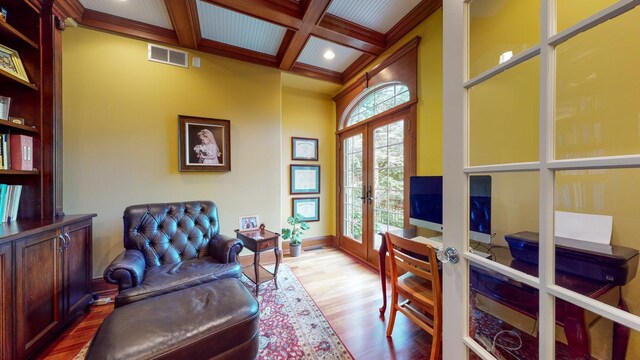 sitting room with crown molding, french doors, beamed ceiling, coffered ceiling, and wood-type flooring