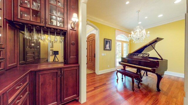 interior space featuring wood-type flooring, a chandelier, and crown molding