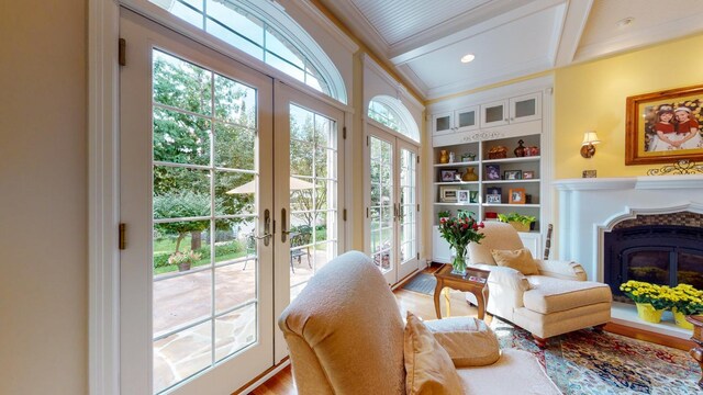 living area with crown molding, french doors, a wealth of natural light, and hardwood / wood-style flooring