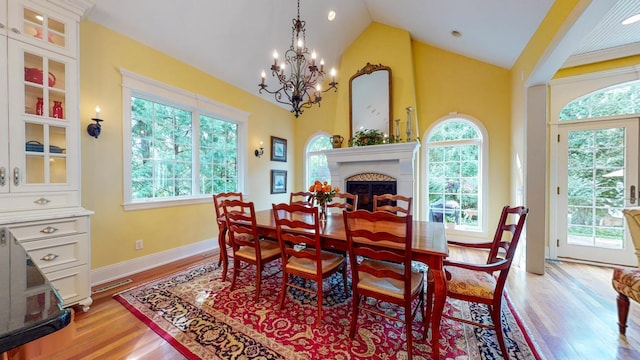 dining area with lofted ceiling, light hardwood / wood-style flooring, and an inviting chandelier