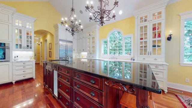 kitchen with dark hardwood / wood-style flooring, a breakfast bar area, plenty of natural light, and an island with sink