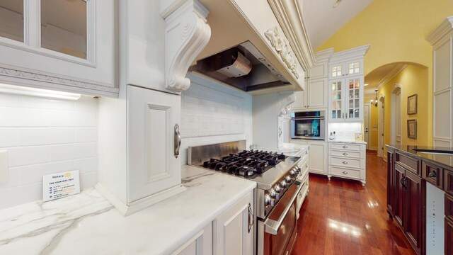 kitchen with high vaulted ceiling, appliances with stainless steel finishes, dark hardwood / wood-style flooring, and white cabinets