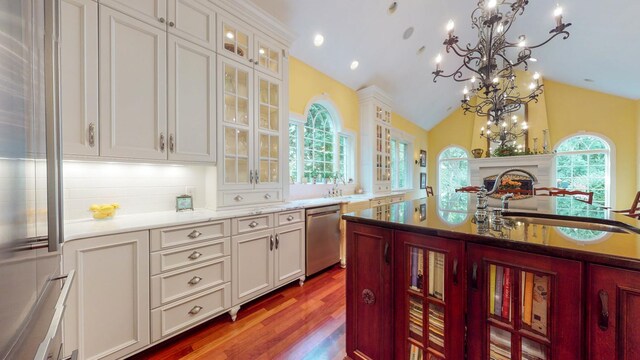 kitchen featuring white cabinets, vaulted ceiling, appliances with stainless steel finishes, a notable chandelier, and sink