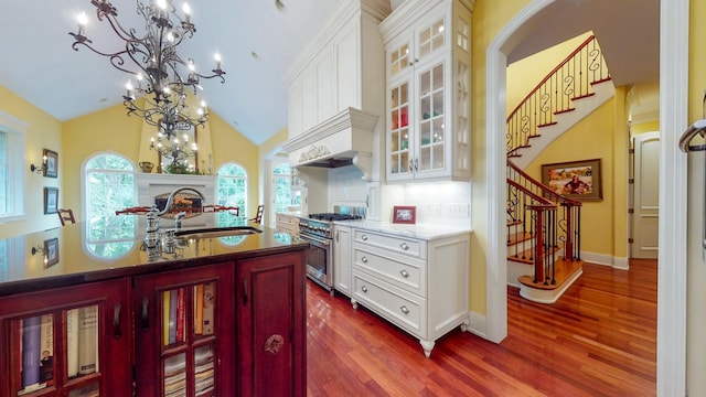 kitchen featuring white cabinets, a chandelier, high end stove, sink, and dark wood-type flooring