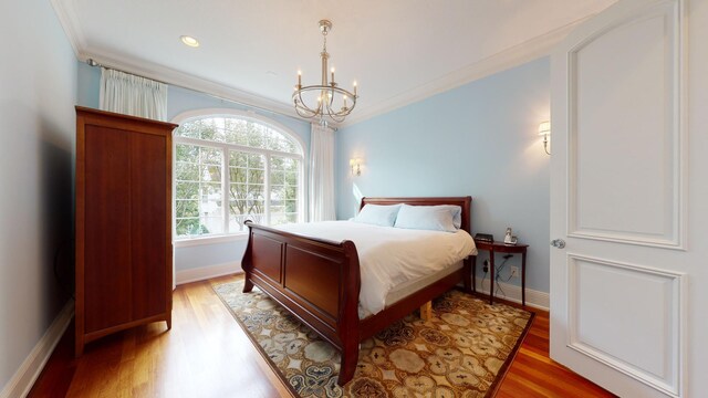 bedroom with crown molding, hardwood / wood-style flooring, and a notable chandelier