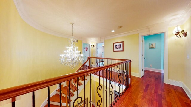 hallway featuring dark wood-type flooring, a notable chandelier, and ornamental molding