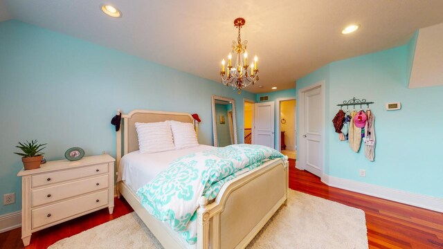 bedroom with wood-type flooring and a notable chandelier