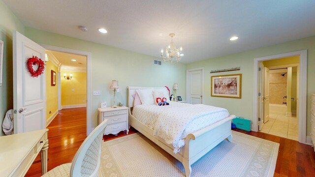 bedroom with a chandelier, ensuite bathroom, and light hardwood / wood-style floors