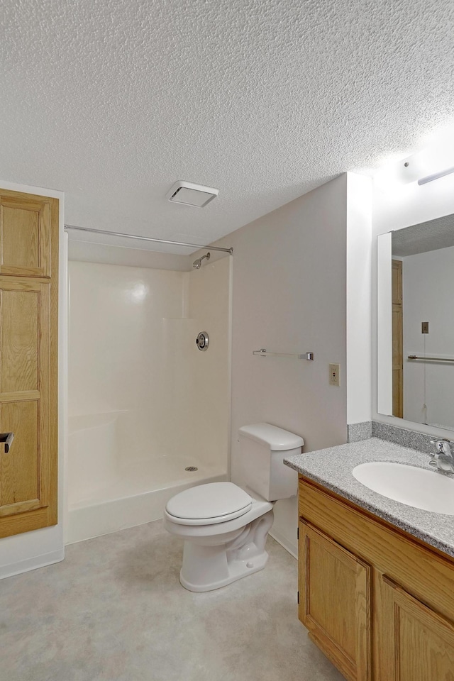 bathroom with vanity, toilet, a shower, and a textured ceiling