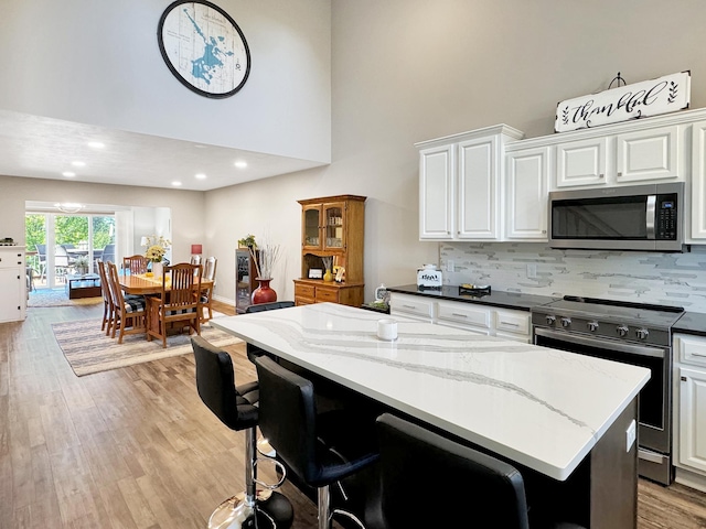 kitchen featuring light stone counters, stainless steel appliances, light hardwood / wood-style floors, and white cabinetry