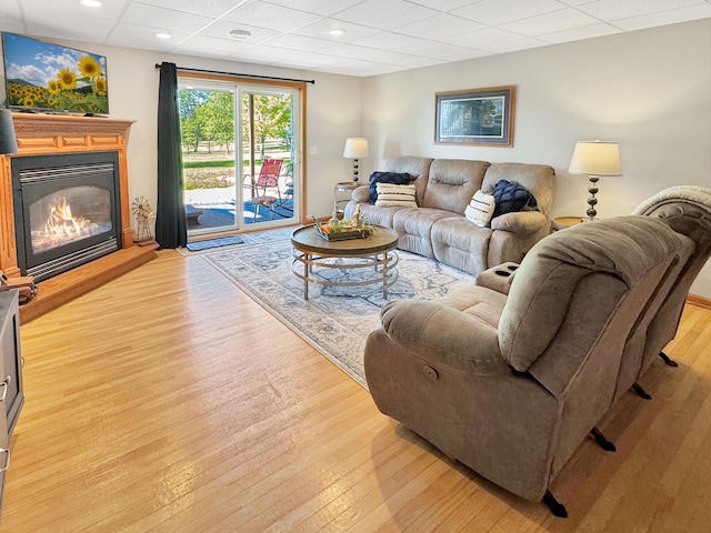 living room with a paneled ceiling and light hardwood / wood-style flooring