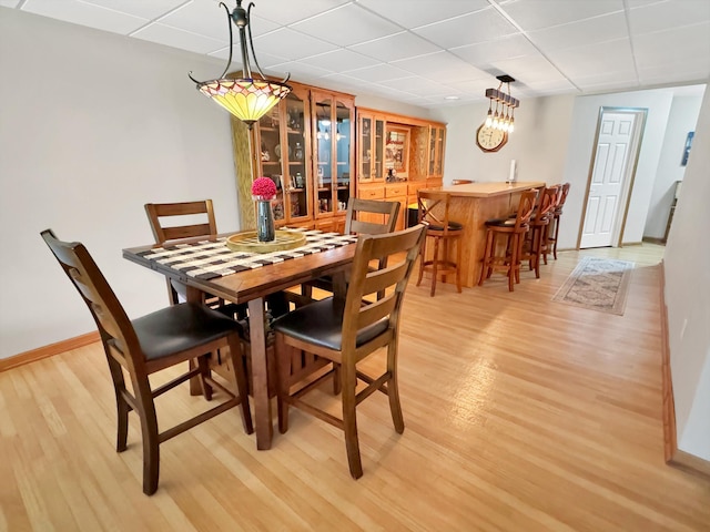 dining room featuring light hardwood / wood-style flooring and a drop ceiling