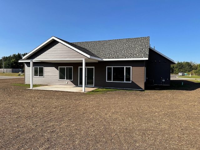 rear view of house featuring a patio area and a shingled roof