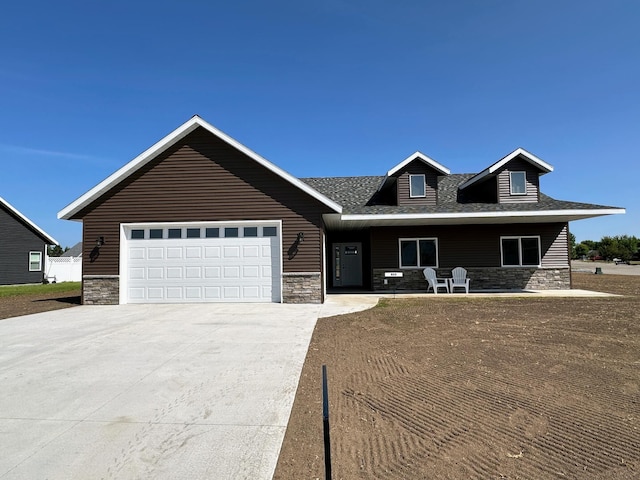 view of front of home featuring an attached garage, stone siding, and driveway