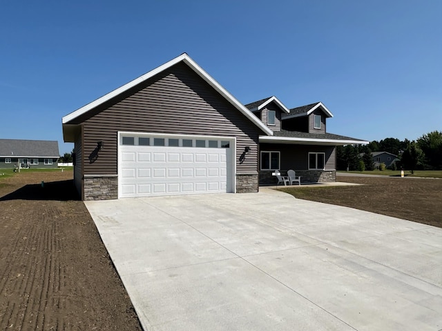 view of front of property with an attached garage, stone siding, and driveway