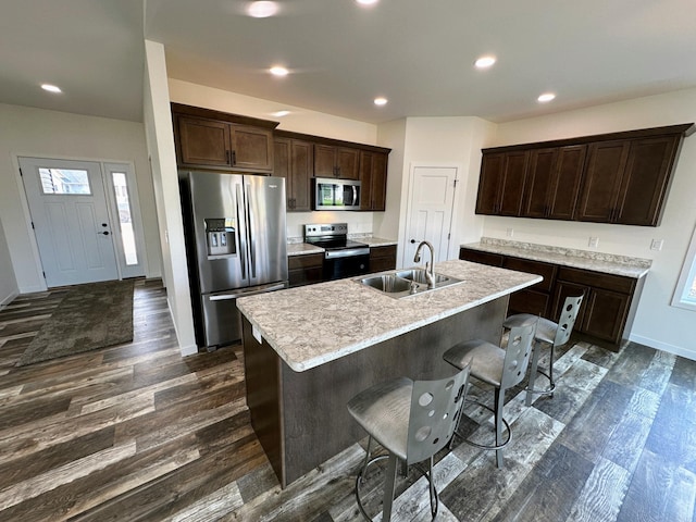 kitchen featuring stainless steel appliances, a kitchen breakfast bar, an island with sink, sink, and dark hardwood / wood-style floors