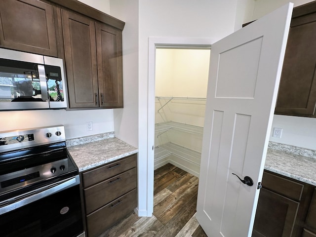 kitchen featuring appliances with stainless steel finishes, dark brown cabinetry, and dark hardwood / wood-style floors