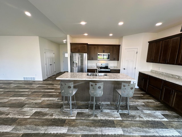 kitchen with a center island with sink, sink, appliances with stainless steel finishes, and a kitchen breakfast bar