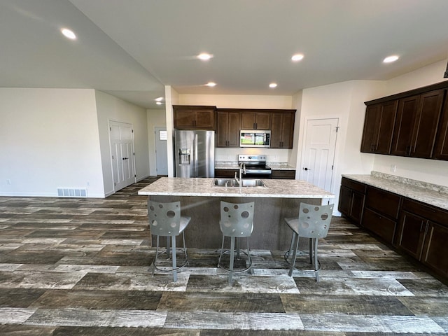 kitchen with visible vents, a sink, an island with sink, dark wood finished floors, and stainless steel appliances