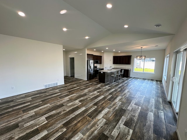 unfurnished living room with dark hardwood / wood-style floors, sink, a notable chandelier, and vaulted ceiling