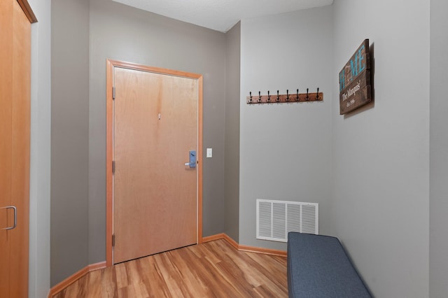 doorway with light hardwood / wood-style flooring and a textured ceiling