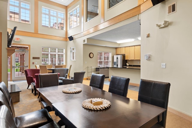 carpeted dining room featuring a towering ceiling and a healthy amount of sunlight