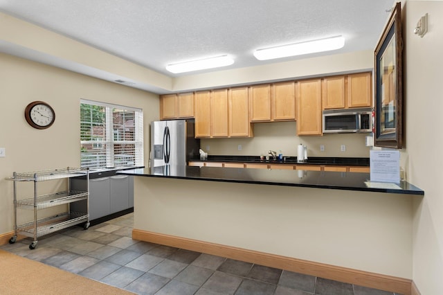 kitchen featuring stainless steel appliances, tile patterned flooring, and a textured ceiling