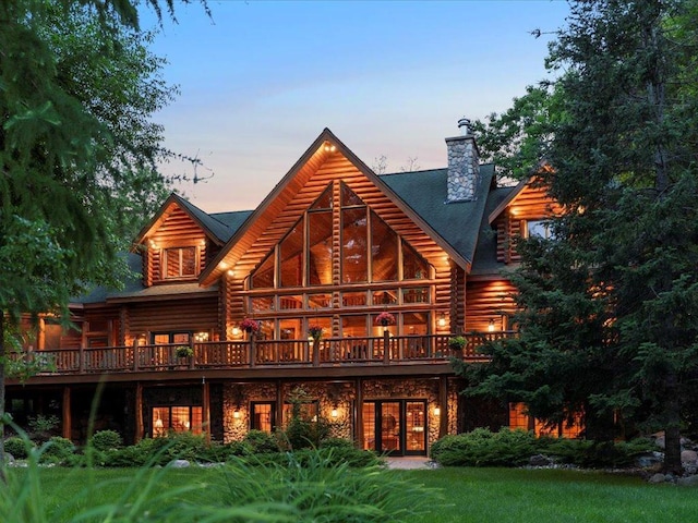 back house at dusk with a deck and a lawn