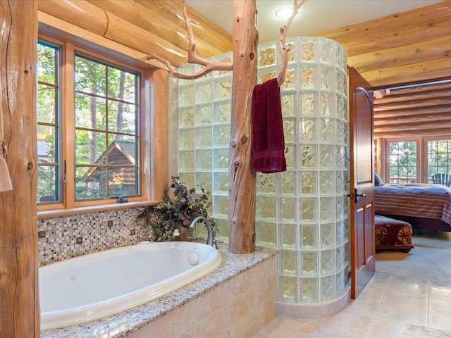 bathroom with plenty of natural light, log walls, and tiled tub