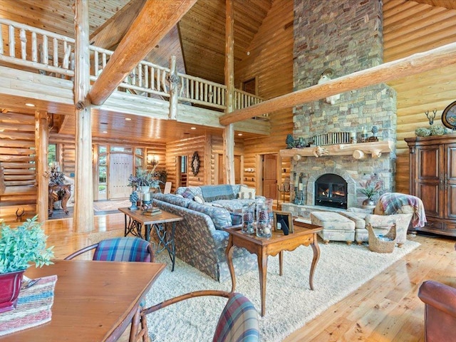 living room with a stone fireplace, wood-type flooring, high vaulted ceiling, and rustic walls