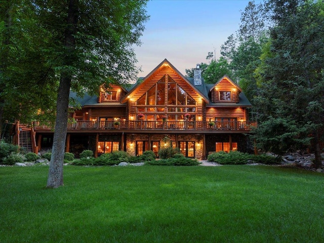 back house at dusk featuring a wooden deck and a yard