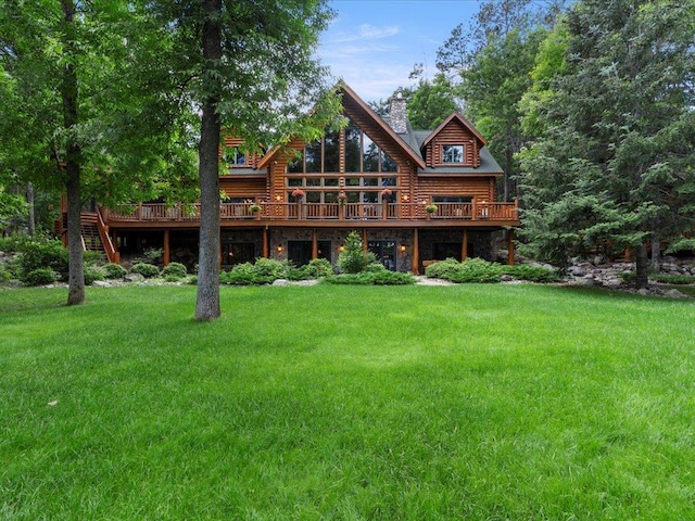 rear view of house with a wooden deck and a lawn