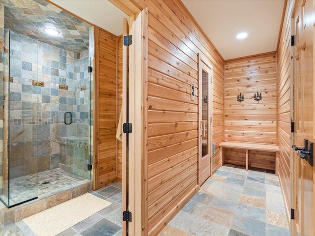 bathroom with a shower with shower door and wood walls