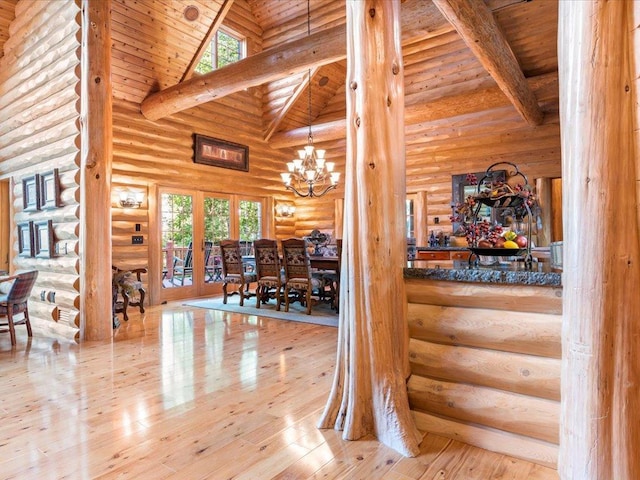 hall featuring a notable chandelier, wood ceiling, high vaulted ceiling, and rustic walls