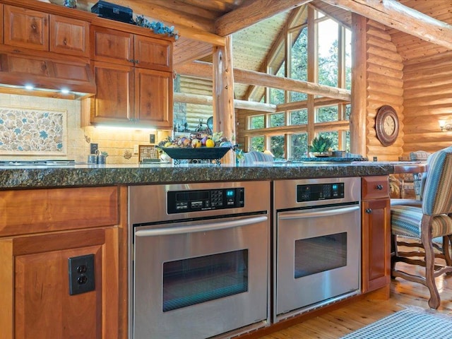 kitchen with beamed ceiling, rustic walls, oven, and backsplash