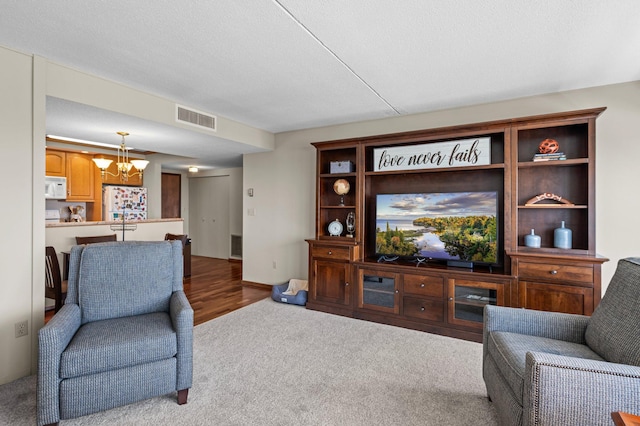 carpeted living room with an inviting chandelier and a textured ceiling