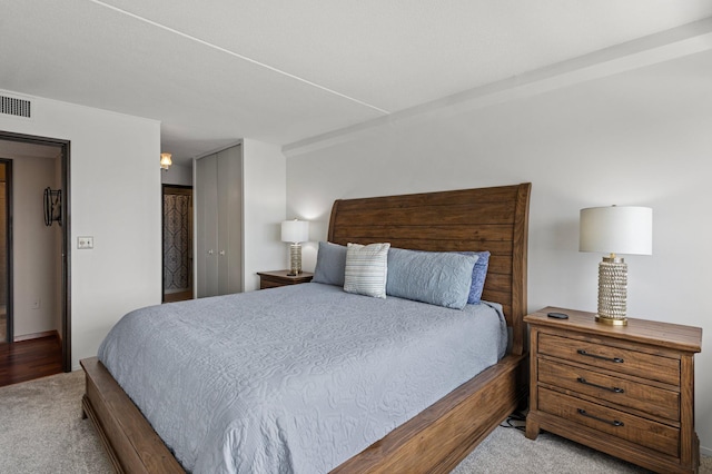 bedroom with a closet, visible vents, and light colored carpet