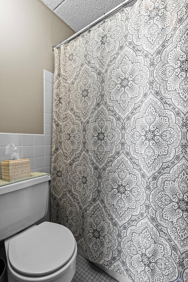 bathroom featuring tile walls, a textured ceiling, walk in shower, and toilet