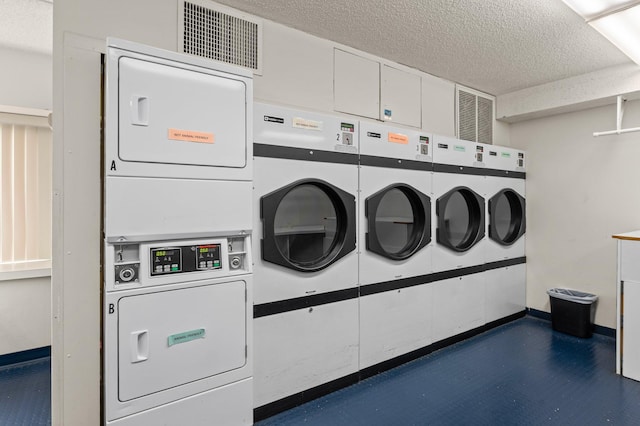 common laundry area with a textured ceiling, stacked washing maching and dryer, visible vents, and baseboards