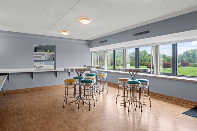 dining area featuring a textured ceiling and light parquet floors