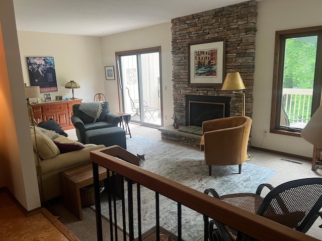 living area with visible vents, baseboards, light colored carpet, and a fireplace