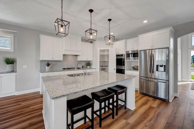 kitchen with appliances with stainless steel finishes, sink, an island with sink, white cabinetry, and dark hardwood / wood-style floors